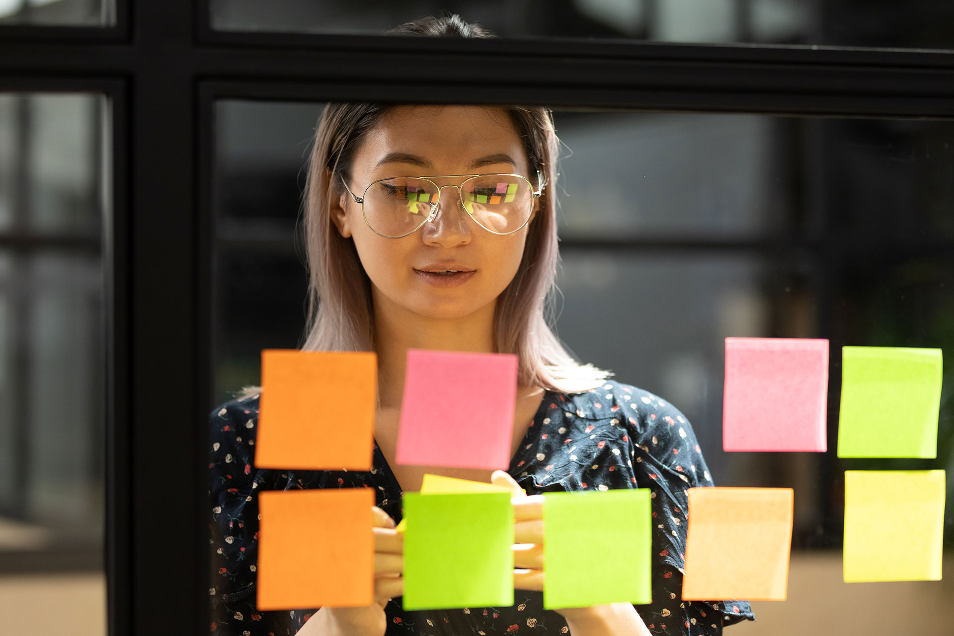 Woman sticking post-it notes on office window